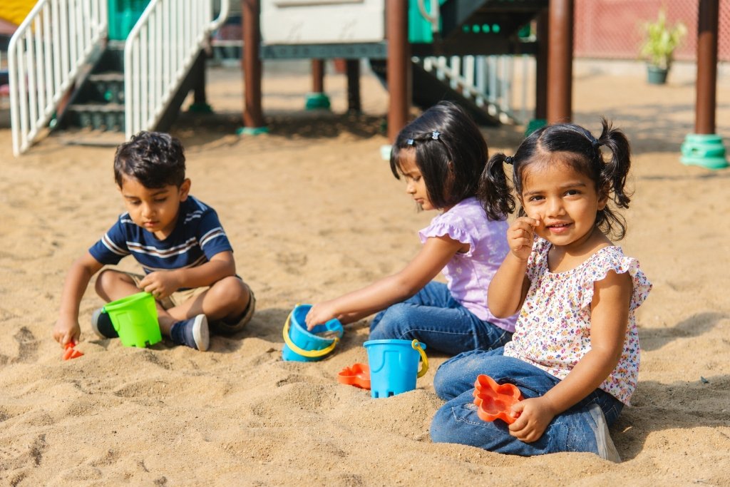Joyful children playing together in outdoor sandpit